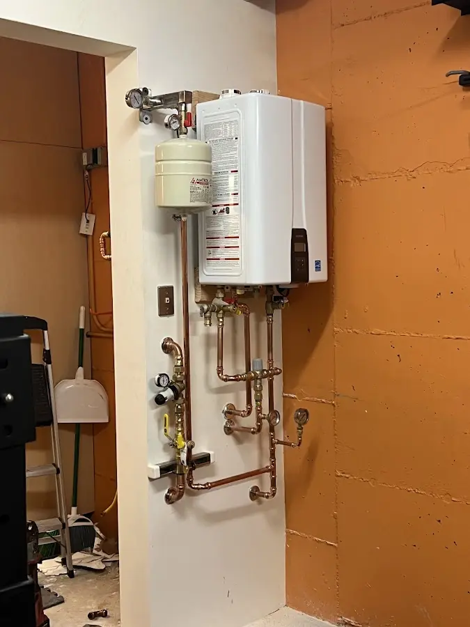 Plumbing technician inspecting water heater connections in Newton